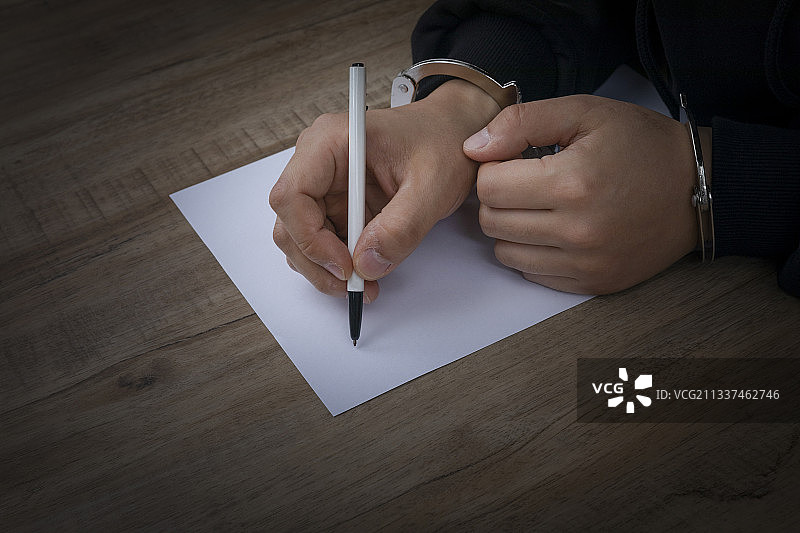 戴手铐的罪犯填写陈述文件图片素材