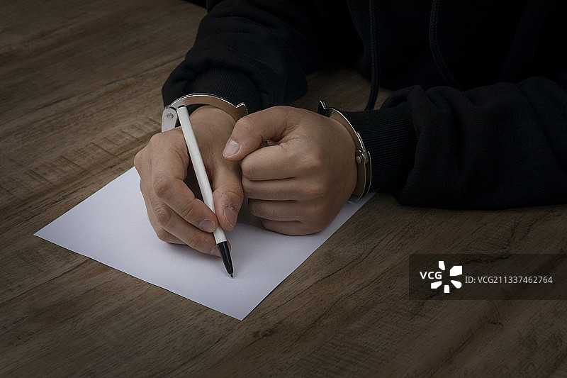 戴手铐的罪犯填写陈述文件图片素材