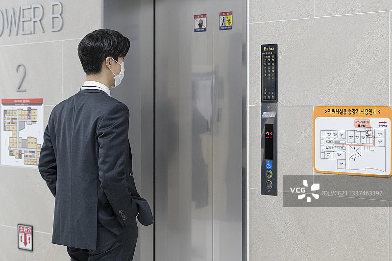 戴着口罩乘坐电梯的亚洲男员工图片素材