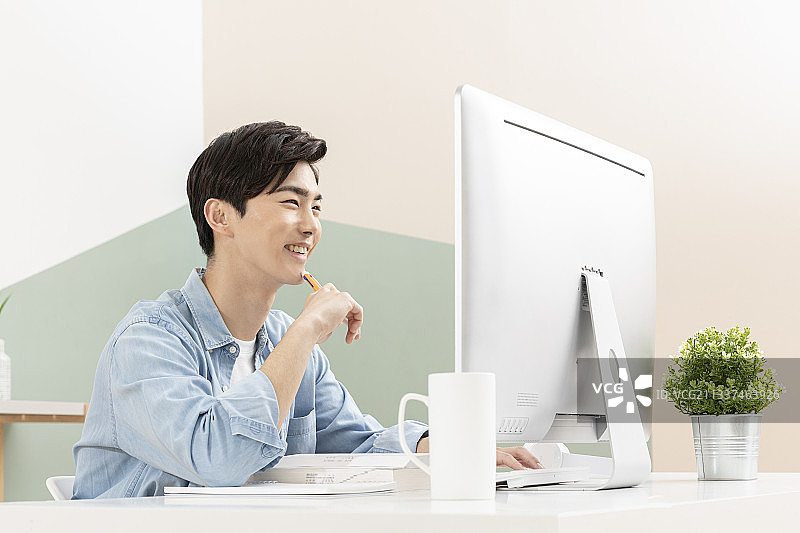 年轻英俊的亚洲男人用电脑学习图片素材