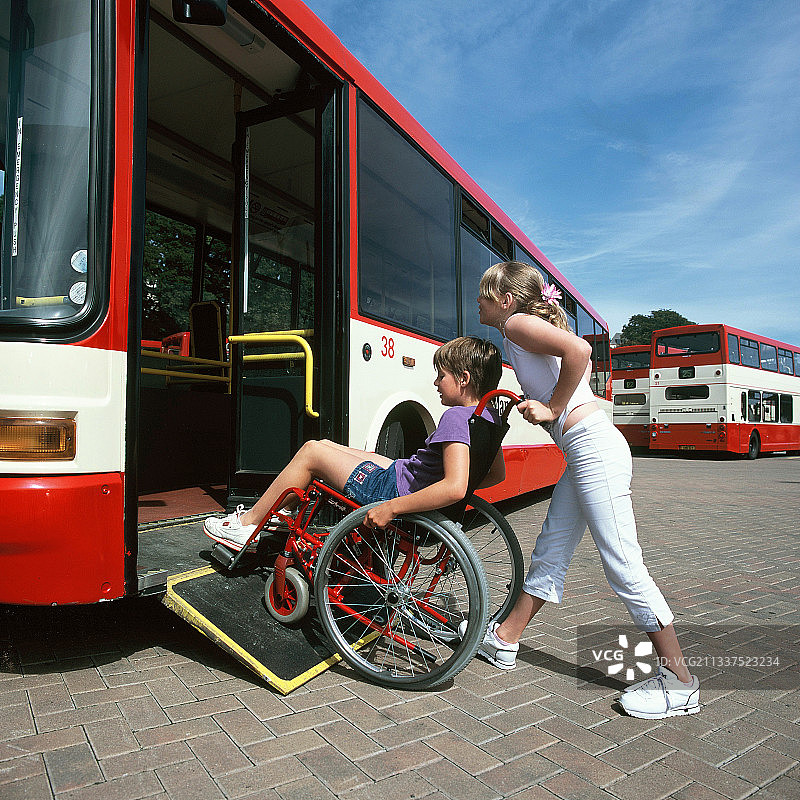 健全的朋友帮助青少年截瘫女孩乘坐公共交通工具图片素材