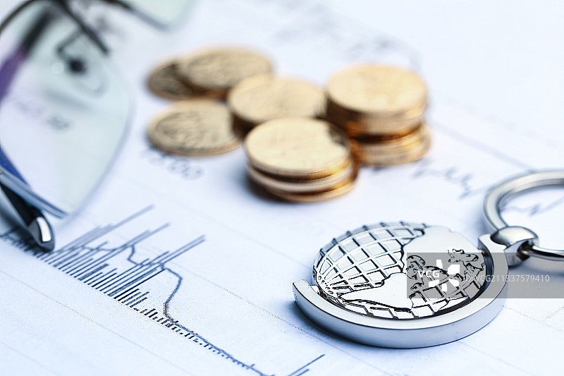 硬币和地球仪钥匙扣放在统计表背景上图片素材