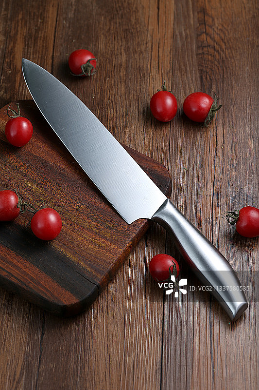不锈钢主厨刀和樱桃西红柿放在桌面上图片素材