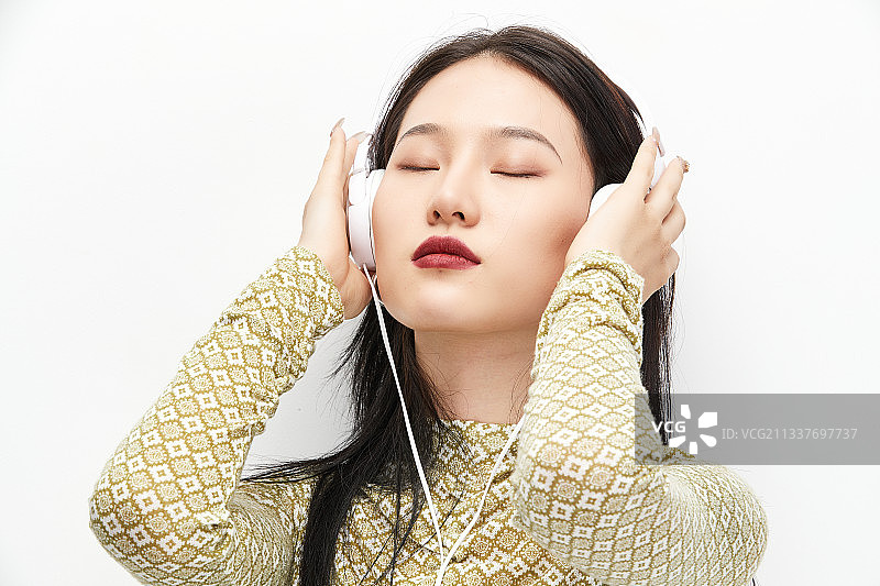 头戴耳机手持电话听音乐的少女图片素材