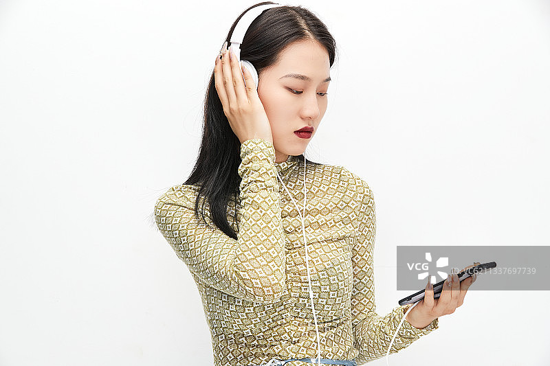 头戴耳机手持电话听音乐的少女图片素材