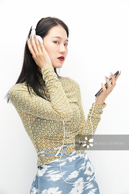 头戴耳机手持电话听音乐的少女图片素材