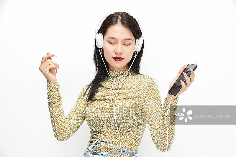头戴耳机手持电话听音乐的少女图片素材