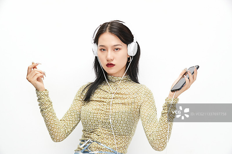 头戴耳机手持电话听音乐的少女图片素材