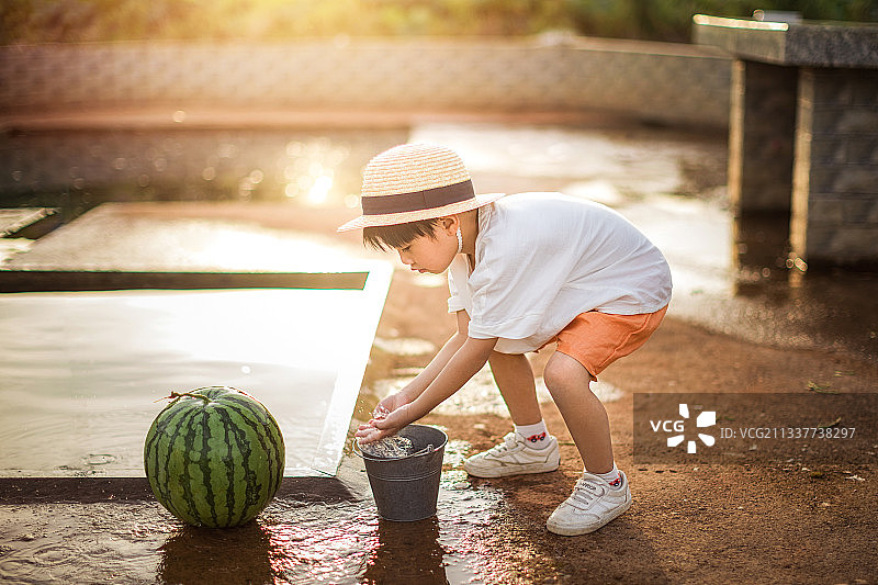 夏天的傍晚水井旁一个洗西瓜的男孩图片素材