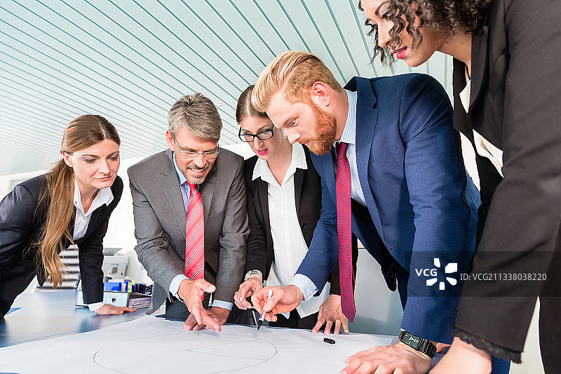 一群商人趴在桌子上分析图表图片素材