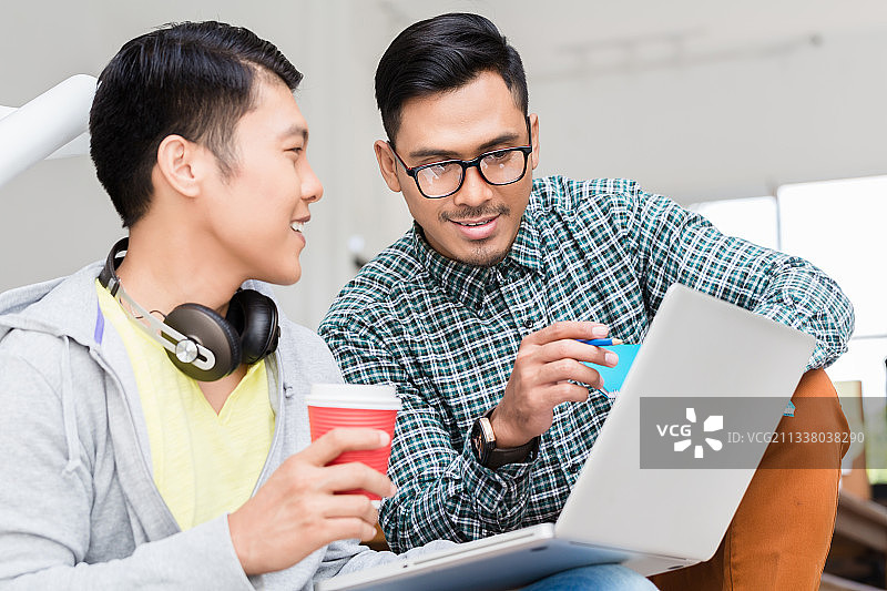 在现代化的办公室里，有经验的员工在笔记本电脑上向同事解释业务信息图片素材