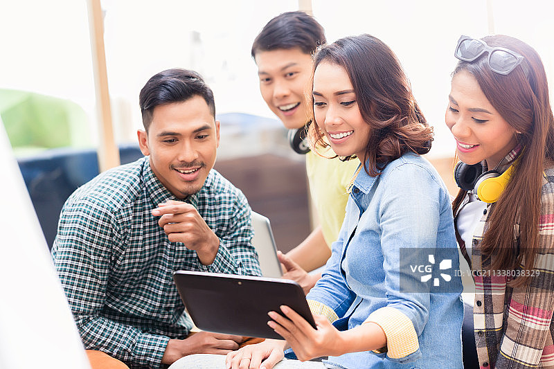 由四名年轻员工组成的创意团队在办公室用平板电脑观看一场令人惊讶的商业演示图片素材