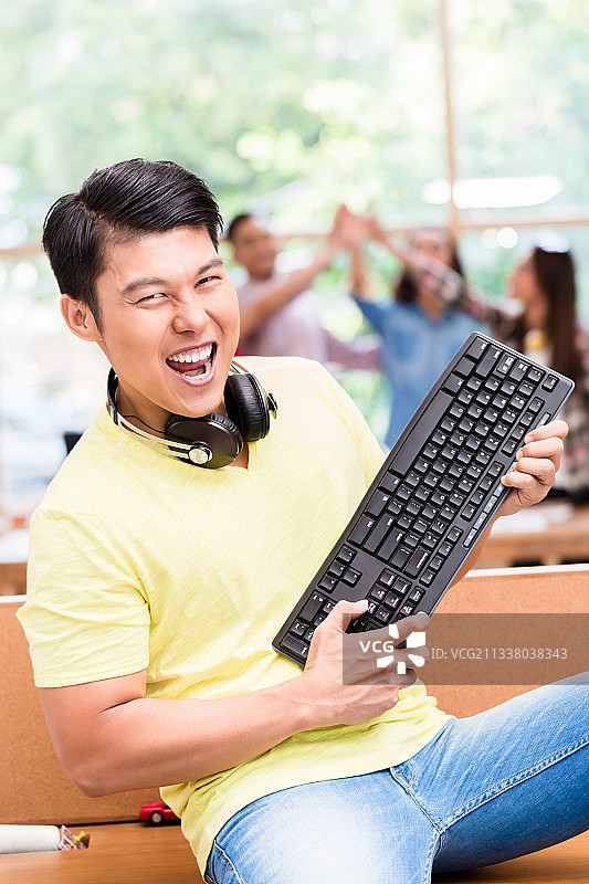 年轻的中国员工为他在电脑上的成功工作和为团队的成功所做的贡献而高兴的肖像图片素材