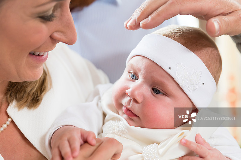 在洗礼仪式上，母亲和婴儿在一起，牧师的手举过婴儿的头顶图片素材