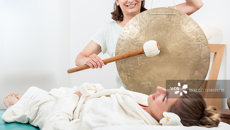 微笑的女人放松在水疗中心，而按摩师制造的声音图片素材