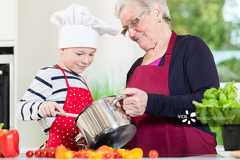 快乐的奶奶和她的孙子一起做饭图片素材