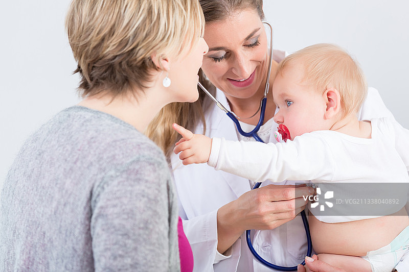 奉献的女医生抱着一个可爱的女婴在她的胳膊在一个现代儿科中心与友好和经验丰富的专家常规访问图片素材