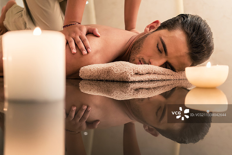 年轻的肌肉男子享受在豪华水疗中心和健康中心的传统泰式按摩的治疗好处图片素材