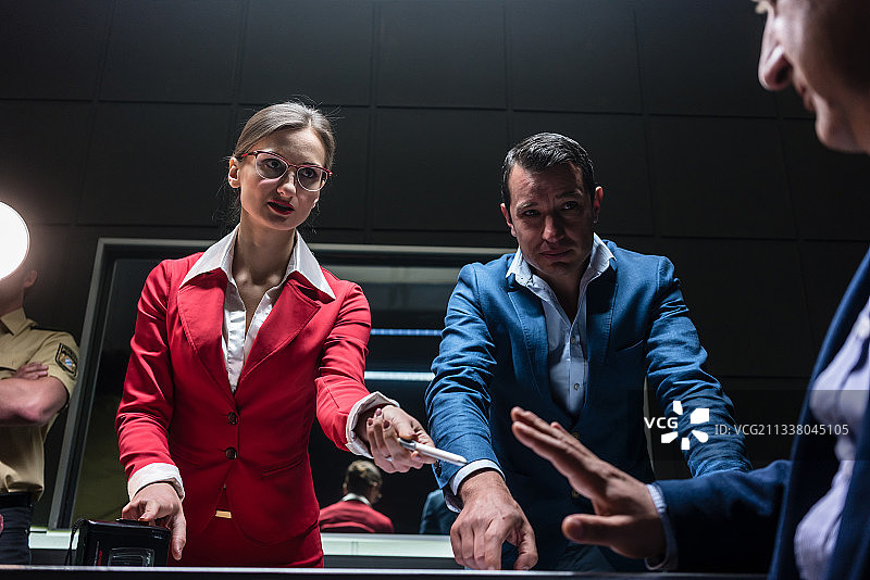 这是两名有说服力的调查人员在警察局试图从一名不情愿的嫌疑人那里获得一份签名供词的低角度照片图片素材