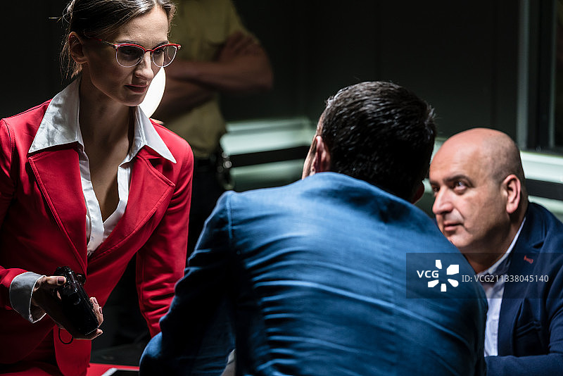 一位专注的女检察官手持录音器，在警察局办公室听一名中年嫌疑人的供词图片素材