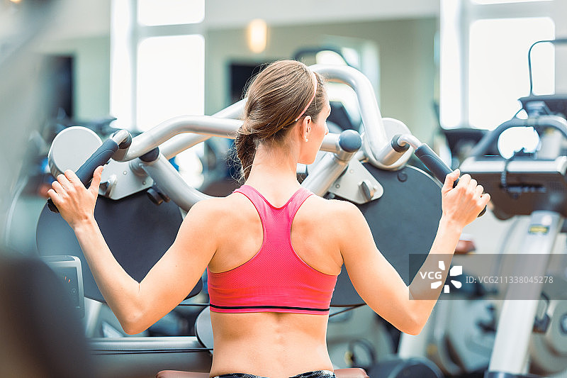 一个决心和美丽的健康的女人在健身房燃烧卡路里锻炼期间骑固定自行车的侧面视图图片素材