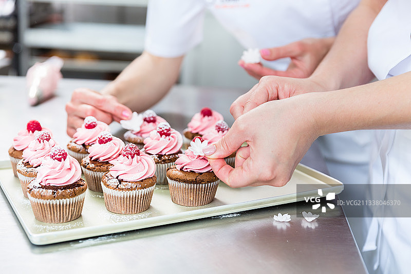 糕点店里的女人们在做松饼，把浆果放在上面图片素材