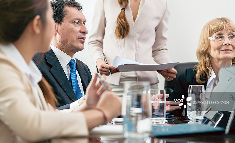 一位西班牙裔中年经理在会议室开会时与同事合作寻找解决方案的侧视图图片素材