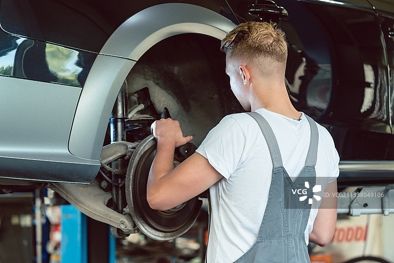 经验丰富的汽车修理工在现代汽车修理厂工作期间更换吊车的盘式制动器，并提供专业的调校服务图片素材