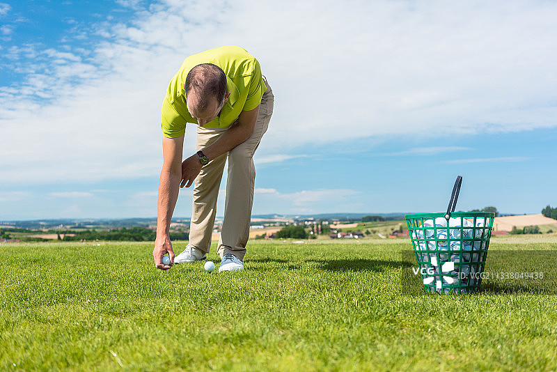 一个职业男性球员的手的特写从一个高尔夫球场的绿色草地上拿球，在一个阳光明媚的夏天的个人比赛图片素材