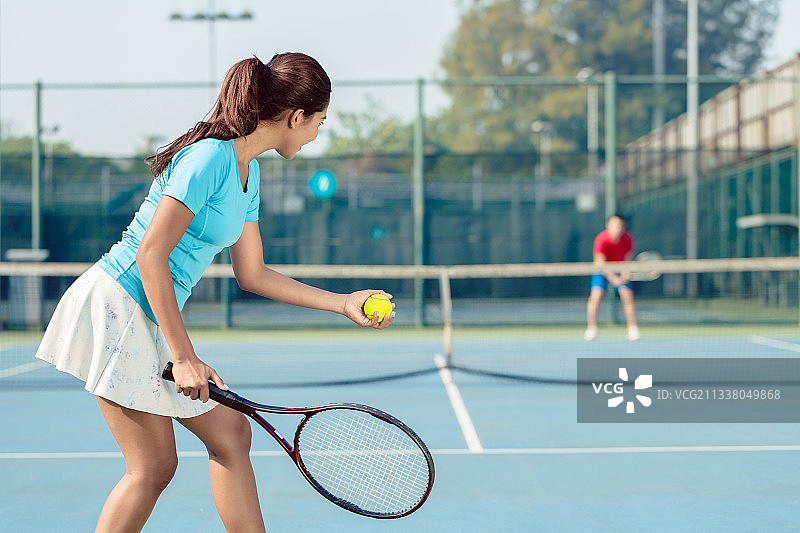 网球比赛中职业女选手在发球前手持球拍和球面带微笑的侧面照片图片素材