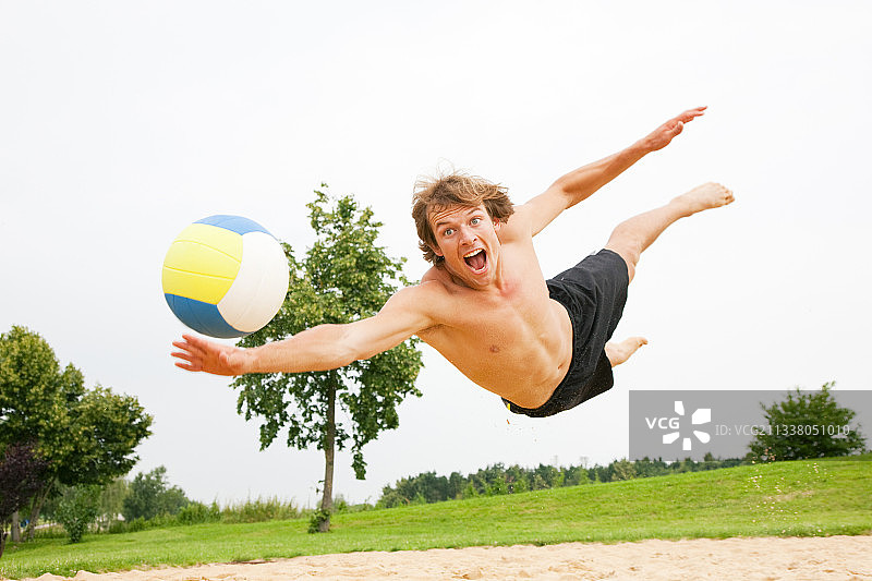 男子在玩沙滩排球跳水后的球图片素材