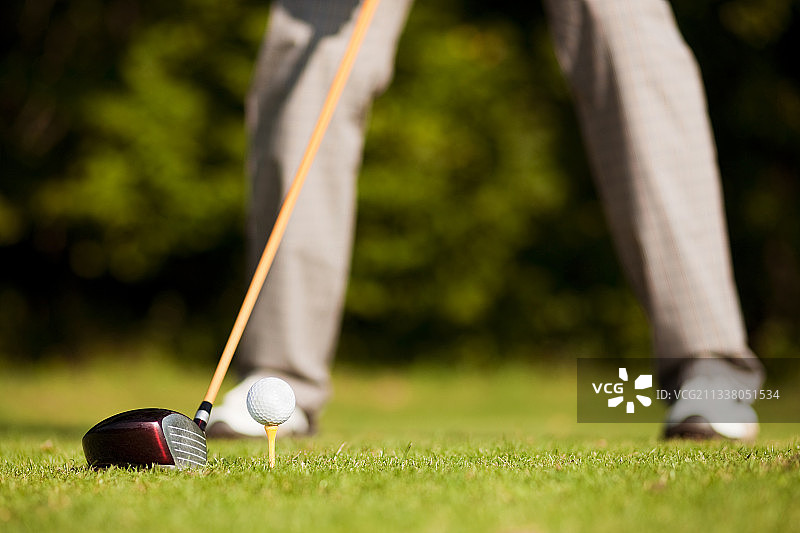 高尔夫球选手在发球区打球(只能看到选手的腿，专注于球)图片素材