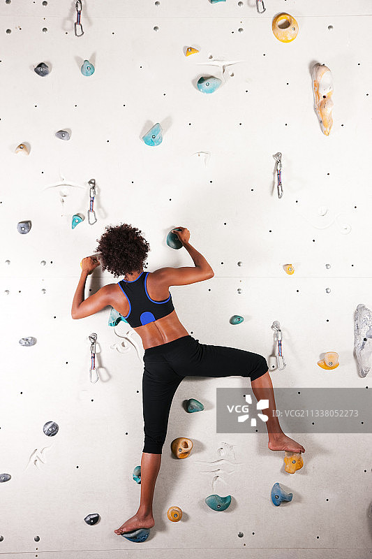 妇女(非裔美国人)在健身房的攀岩墙上锻炼图片素材
