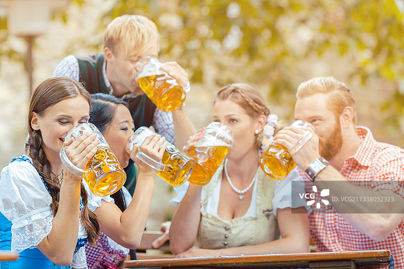 四个朋友同时在巴伐利亚啤酒花园喝啤酒图片素材