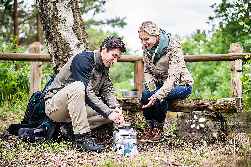 男人和女人在徒步旅行中休息，在野营炉上准备食物图片素材