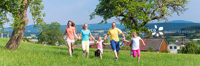 父亲和孩子们在绿草地上奔跑图片素材