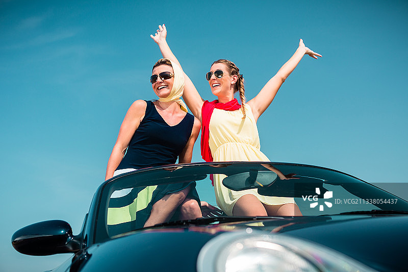 一个女人在敞篷车里进行夏季旅行，她的手在空中伸得很开心图片素材