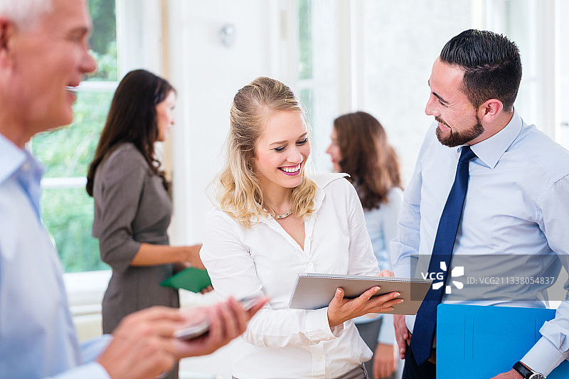 商务人员在办公室团队工作，女性展示男性在平板电脑上的演示图片素材