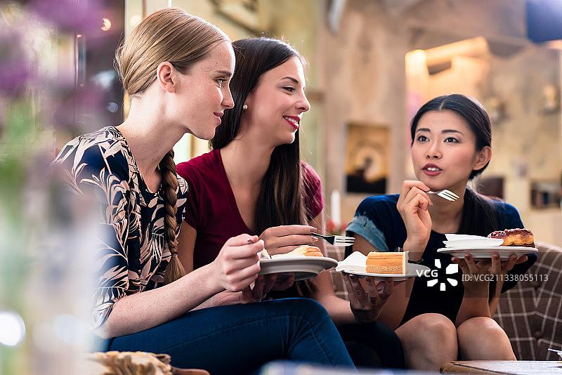 三个年轻的女人分享意见和想法，同时吃蛋糕室内图片素材