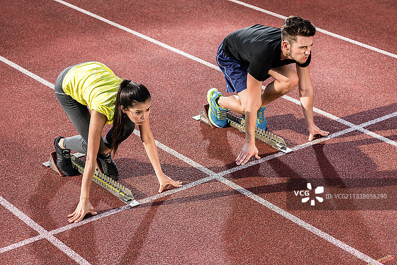 男女运动员在起跑点的煤渣跑道上图片素材
