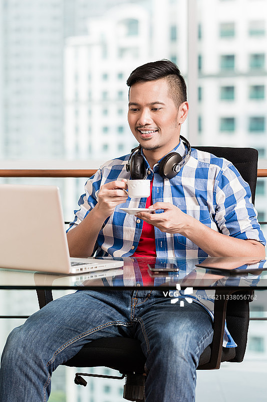 年轻的印尼专业人员在城市办公室的笔记本和喝咖啡图片素材