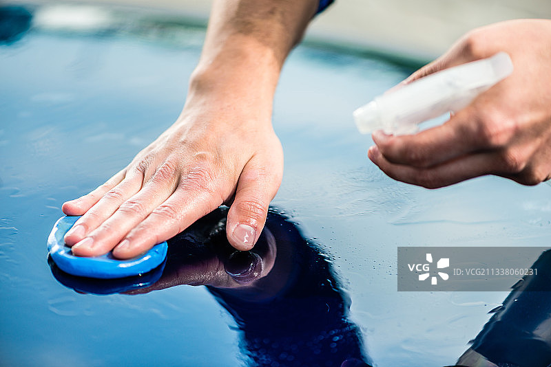男性的手在自动洗车表面打蜡的特写图片素材