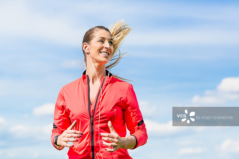 在蓝天下，女人为了更好的健身而慢跑图片素材