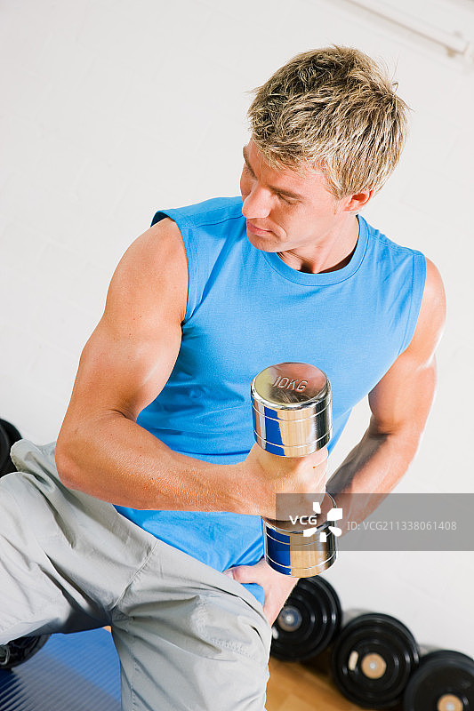 在健身房用哑铃锻炼的年轻人图片素材