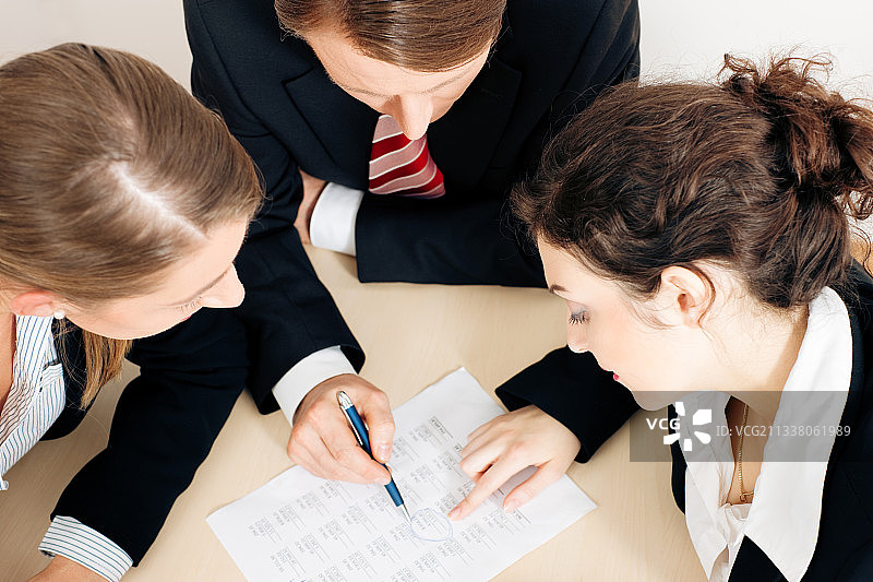 三个人一起讨论一个刚成立的公司的商业计划，重点是文件图片素材