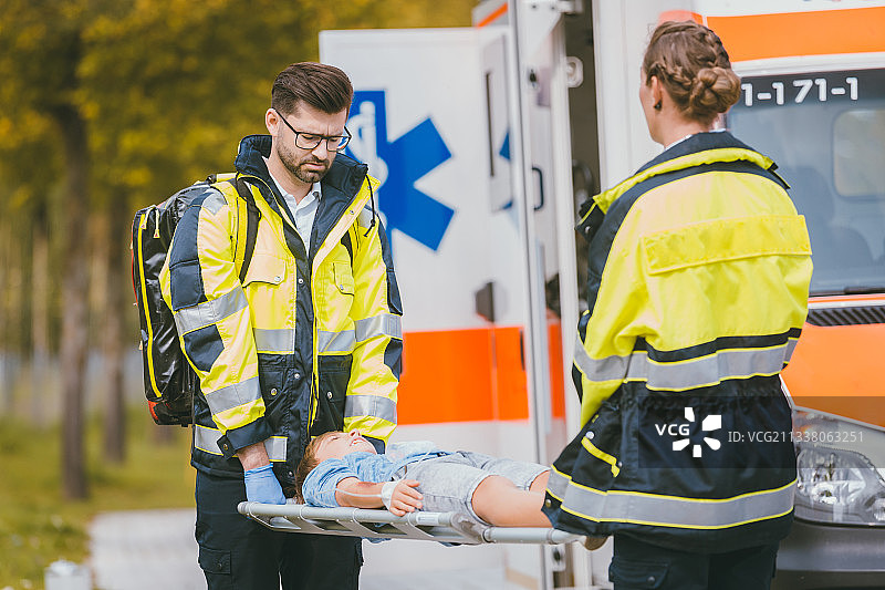 在救护车前面发生事故后，医护人员把受伤的男孩放在担架上图片素材