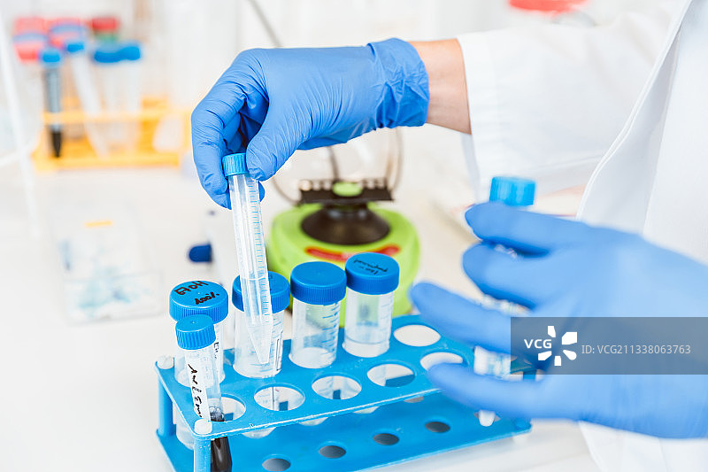 年轻的女科学家戴着蓝色手套拿着试管在临床实验室研究的特写图片素材