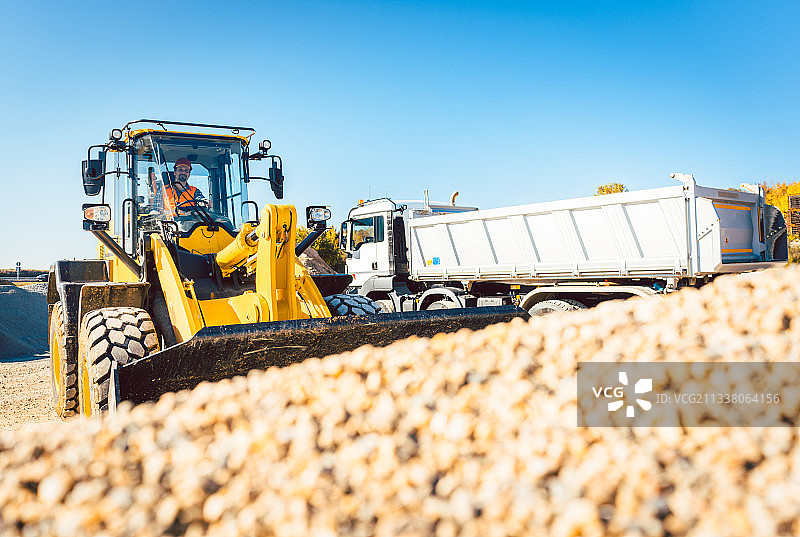 建筑工人正在用装载机和碎石车进行土方工程图片素材