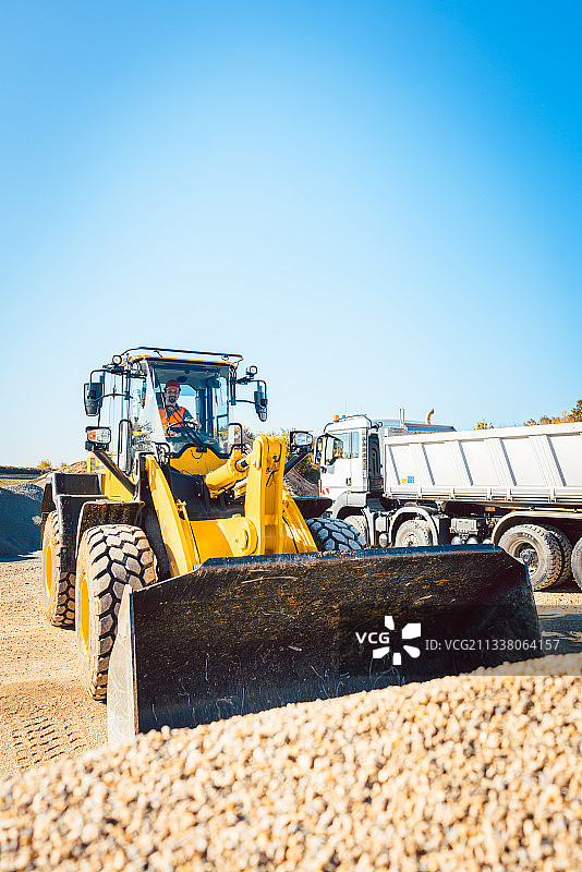 建筑工人正在用装载机和碎石车进行土方工程图片素材
