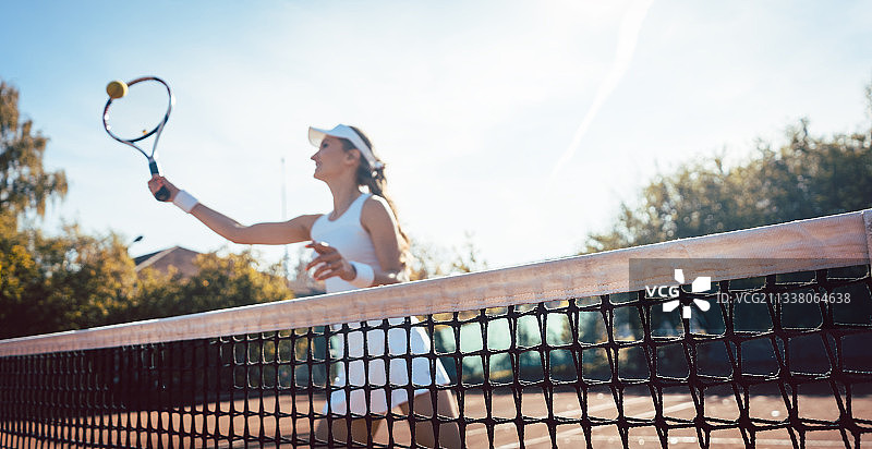 女子在网球场上把球接近网图片素材